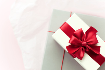 Gift box/ present with red bow on white/pink background. Festive backdrop for holidays: Birthday, Valentines day, Christmas, New Year. Flat lay