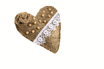 On a white background lies a handmade heart-shaped ornament from improvised materials