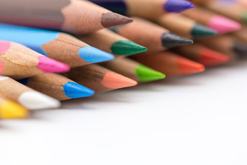 close up colored crayons stacked on whive background concept photo