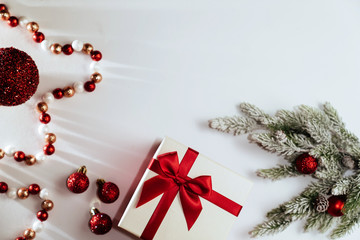 Christmas composition. Christmas gift, knitted blanket, pine cones, fir branches on wooden white background. Flat lay, top view, copy space