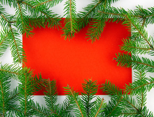 It's Christmas time! Red card on a white background with a frame of branches of Christmas tree. Top view.