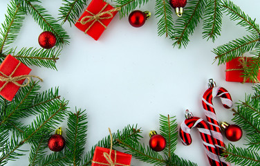 It's Christmas time! Red card on a white background with a frame of Christmas tree branches and festive red decorations. Top view.