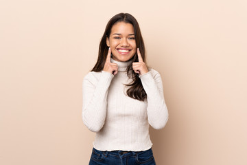 Young Colombian girl over isolated background smiling with a happy and pleasant expression