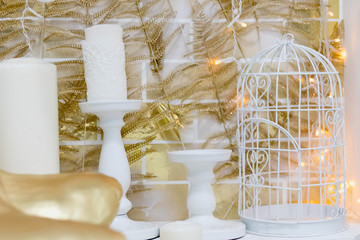 white cage with candlesticks and white candles with gold leaves