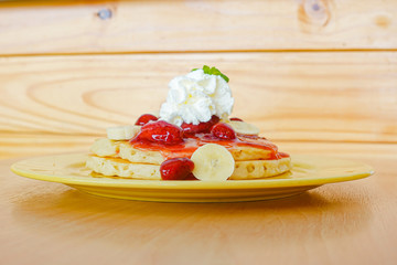 Pancakes served with banana, strawberry, strawberry jam and whipped cream