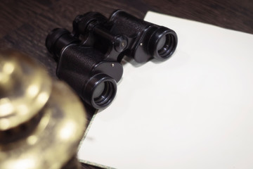 vintage binoculars on a dark wooden background with an open book with blank blank pages