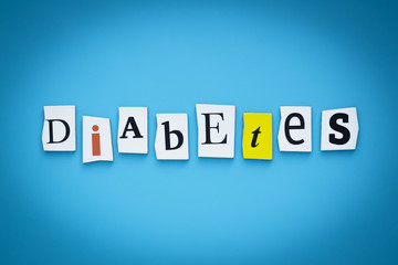Text - diabetes. Single word. Cut paper letters on blue background. Writing on card. Inscription, message on banner