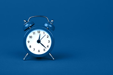 Close up one classic alarm clock over blue background