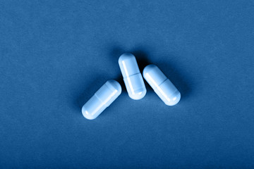 Close up three gel cap pills over blue background
