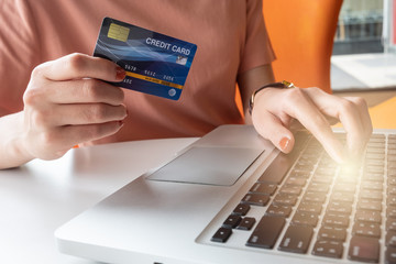 Close up of someone hand holding credit card during using laptop for online shopping. Online shopping is the process of buying goods and services from merchants over the Internet.