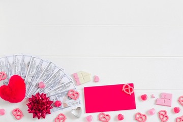 Valentine's composition background, red ribbon, heart, 100 dollar bills cash money, pink chocolate, candy on white wooden table background, Valentine's money gift, copy space for card or banner design