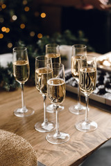 Group of glasses of luxury champagne on a wooden table. White wine in glasses of champagne against the background of a Christmas tree and garland lights