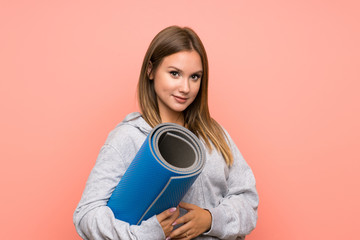 Teenager sport girl with mat over isolated pink background