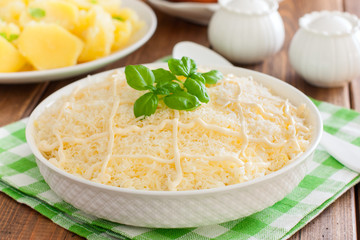 Puff salad with chicken and cheese under mayonnaise on a white plate, selective focus