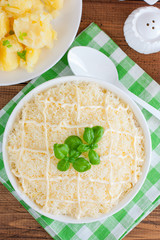 Puff salad with chicken and cheese under mayonnaise on a white plate, selective focus
