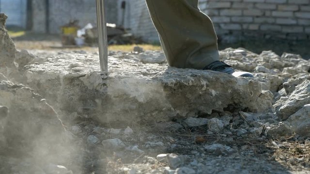Worker smashes concrete with a jackhammer. Crushing concrete slabs from the road to small stones