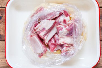 Step-by-step preparation of pork ribs with potatoes in the oven, step 3 - putting all the ingredients in a baking dish, top view, selective focus