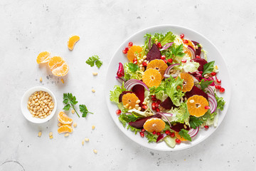 Christmas salad with boiled beet, red onion, tangerines, pomegranate, parsley, pine nuts and lettuce leaves - obrazy, fototapety, plakaty
