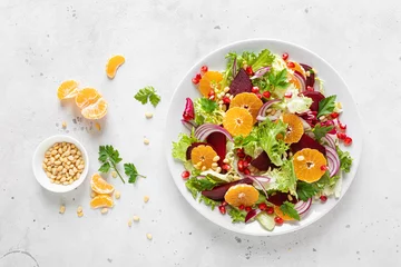 Foto auf Glas Christmas salad with boiled beet, red onion, tangerines, pomegranate, parsley, pine nuts and lettuce leaves © Sea Wave