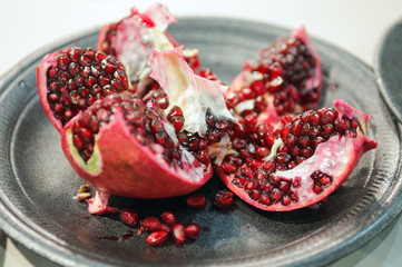 Ripe pomegranate fruit with selective focus on silver plate.