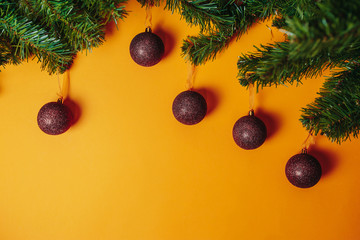 Christmas card with copy space. Christmas ornaments flat lay on the orange background. Red balls and fir branches around.