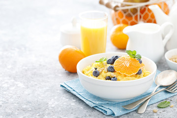 Corn porridge with fresh blueberry, orange and pine nuts in bowl served for breakfast