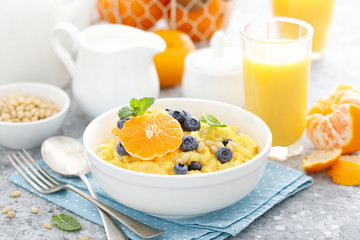 Corn porridge with fresh blueberry, orange and pine nuts in bowl served for breakfast