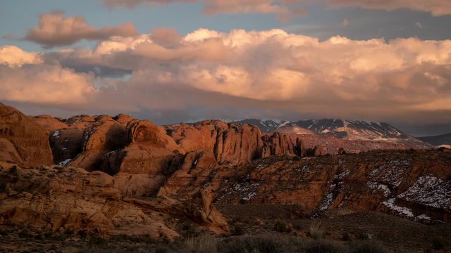Timelapse of colorful sunset over desert rocky fin layers in Moab looking towards the La Sal Mountains as the clouds change colors.