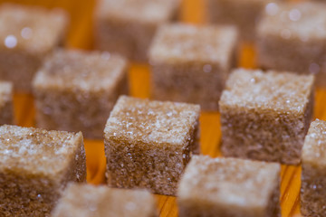 Brown sugar cubes in row on pine wood table close up macro shot for background.