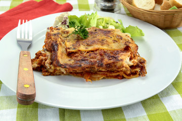 lasagna with bolognese and green salad on a plate