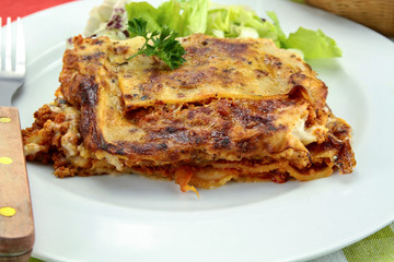 lasagna with bolognese and green salad on a plate