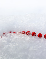 Red beads on fresh white snow. Background for Christmas and New Year