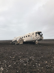Crashed and abandoned plane on black sand