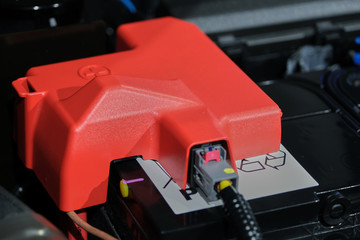 plastic cover of the positive battery cell tip with the red plus symbol, the battery is placed in the engine compartment.