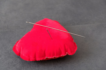 red pincushion and big sewing needle,