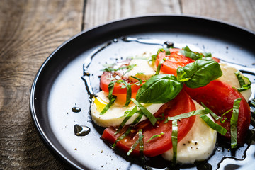 Caprese salad on black plate on wooden table