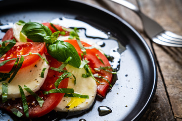 Caprese salad on black plate on wooden table