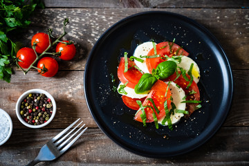 Caprese salad on black plate on wooden table