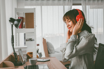 Beautiful asian woman listening music at home in the room, enjoying concept.