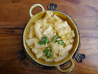 Noodles served on metal plate with Alfredo sauce and grated Parmesan cheese