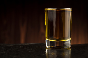 glass of whiskey on the table on wooden background