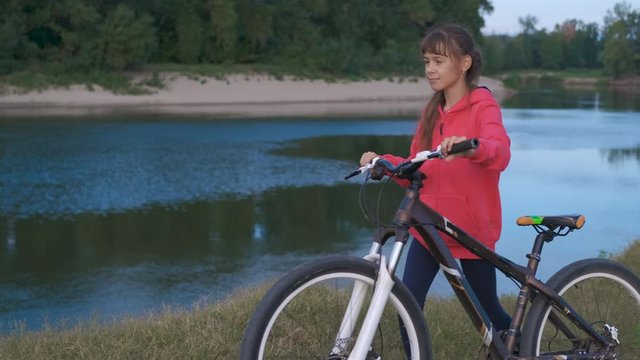Girl with a bicycle by the river.