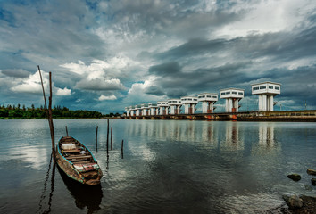 Obraz premium Fishing boat and water barrier and river with cloud sky storm in rain season