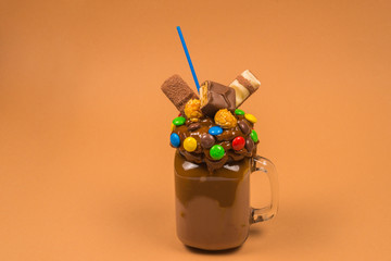 Chocolate milkshake with whipped cream, cookies, waffles, served in glass mason jar. 