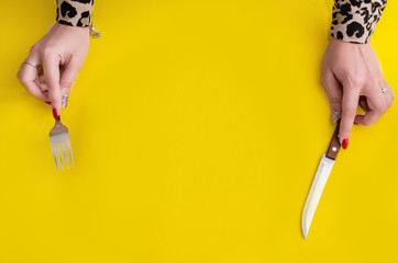 .Top view girl holding a fork and knife on a yellow background