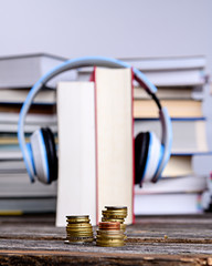 book with headphone and money in front of piles of different books