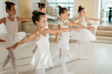 Young happy caucasian little ballerinas, awesome ballet dancers practicing some dance element in a dance class. Professional school of ballet dance for kids, chiildren © alfa27