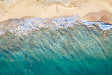 Ocean beach aerial top down view with blue water, waves with foam and spray and fine sand, summer...