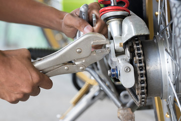 Technicians use locking pliers to unscrew screws to fix the motorcycle.