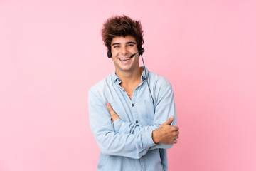 Young caucasian man over isolated pink background working with headset